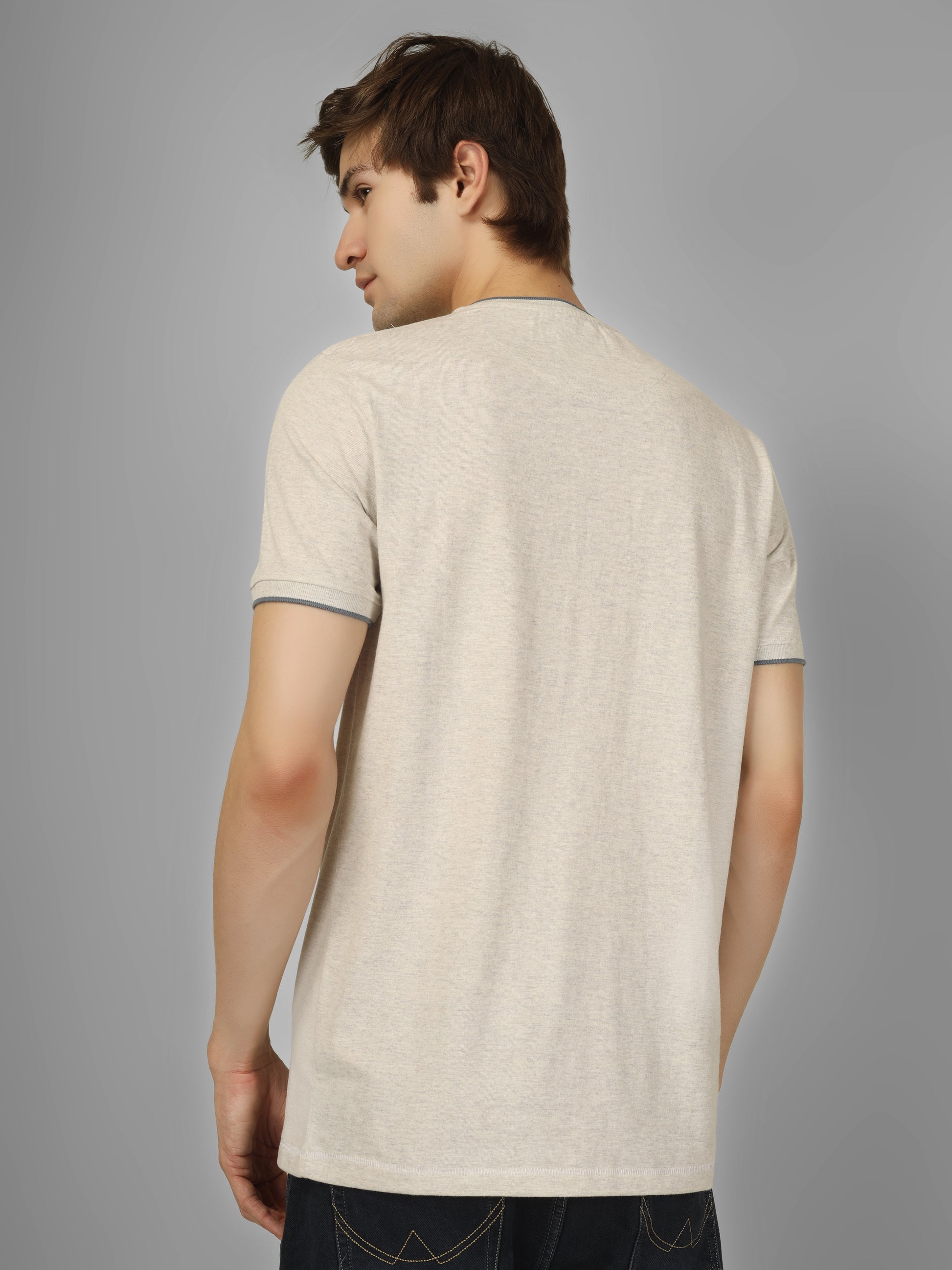 Man wearing a beige t-shirt against a gray background